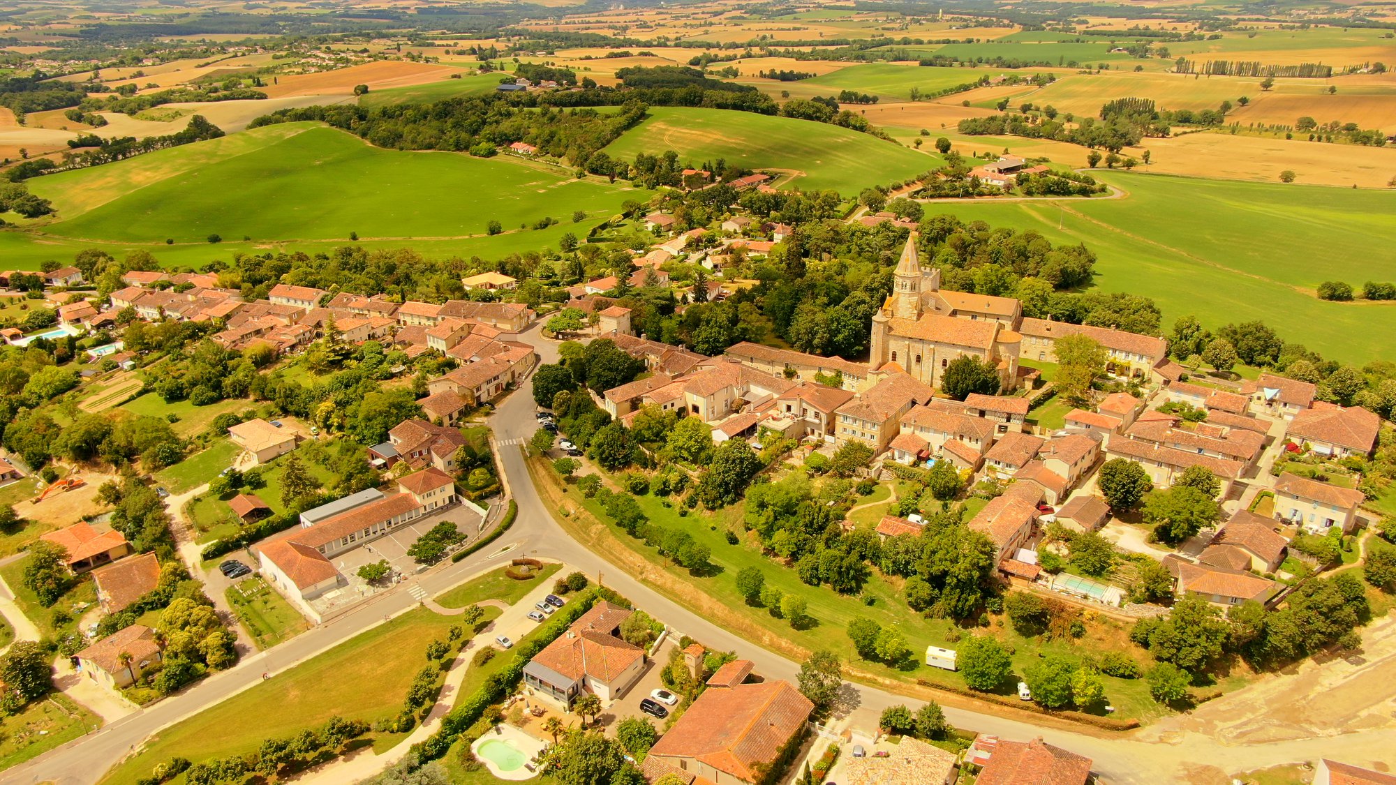 Montaut-les-Créneaux : au premier plan, l'école primaire avec, de l'autre côté de la route, l'emplacement herboré où se tiendra le marché - © Laurent Lainé