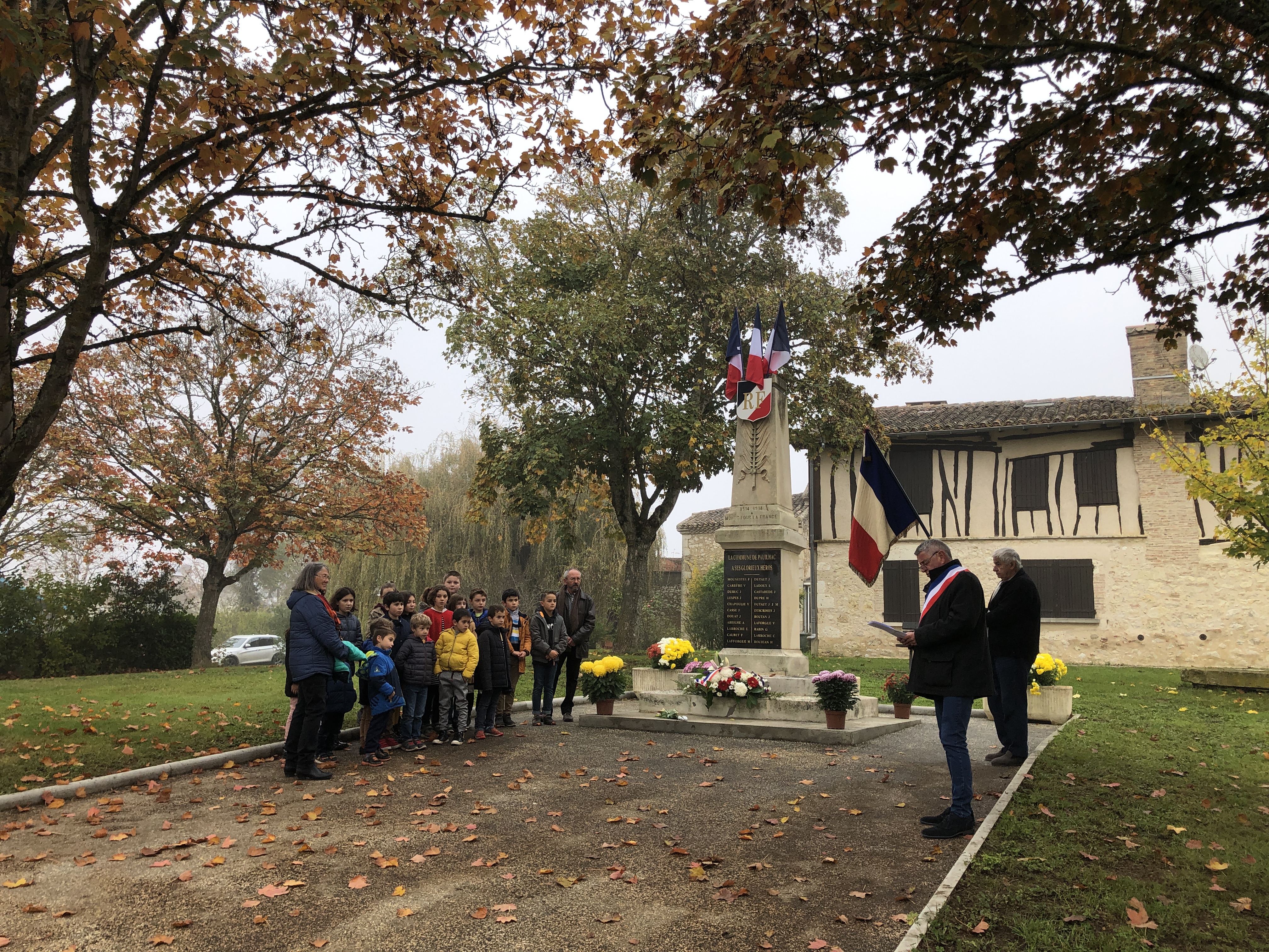 Devant le monument aux morts, le maire de Pauilhac M. Suarez, M. Claude Menegazzo et les enfants de l'école avec les époux Delmas.