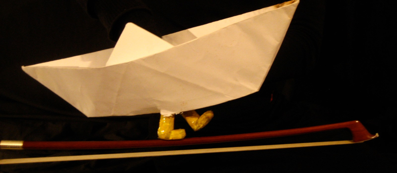 Des bottes, une tête lisse comme un galet, un bateau en papier dans les profondeurs d'un rêve